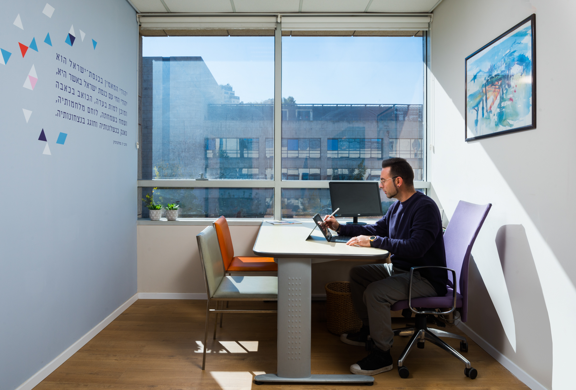 Interior designer Yuri Nulman, seating in front of a desk and sketching on an i pad.