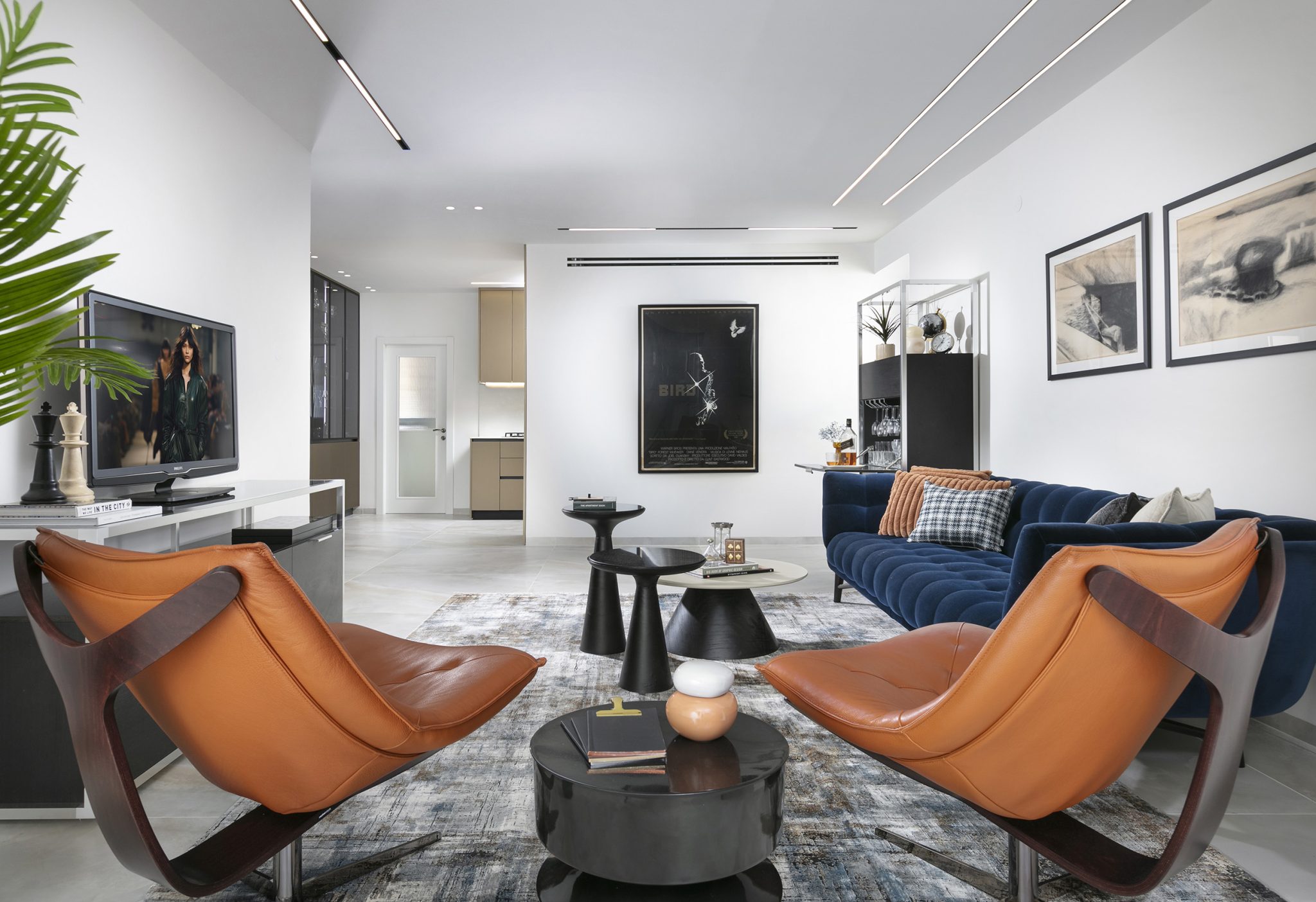 Interior space of a living room designed in a modern elegant style. Two brown leather armchairs and a blue navy sofa.